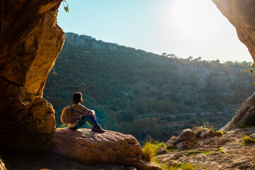 happy woman in the mountains. girl resting sitting on a stone in the mountains. trekking and hiking. concept of sports and healthy lifestyle.