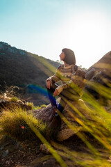 happy woman in the mountains. girl resting sitting on a stone in the mountains. trekking and hiking. concept of sports and healthy lifestyle.