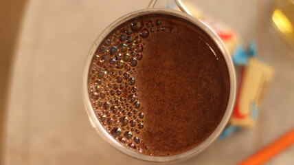 A travel metal mug with hot coffee on a bright table.Close-up