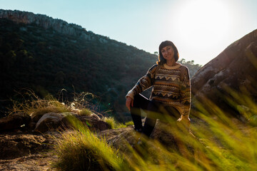 happy woman in the mountains. girl resting sitting on a stone in the mountains. trekking and hiking. concept of sports and healthy lifestyle.