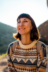 Portrait of happy female tourist in mountains. girl smiles. trekking and hiking. girl with backpack.