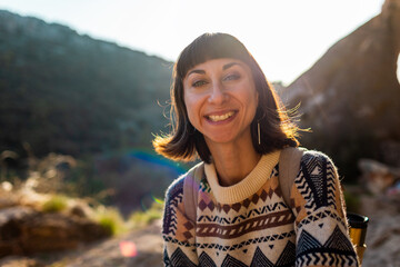 Girl with backpack. Portrait of happy female tourist in mountains. Trekking and hiking.