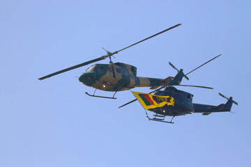 bell 212 rescue helicopter in camouflage colours and  black bell 412 helicopters are flying formation with national flag of sri lanka