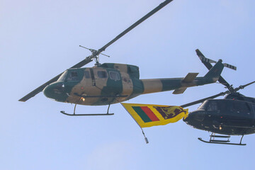 bell 212 rescue helicopter in camouflage colours and  black bell 412 helicopters are flying formation with national flag of sri lanka
