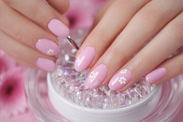 Creative nail art session featuring pink polish and delicate floral designs with a sparkling background