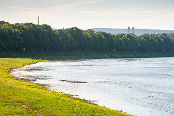 embankment of the river uzh in morning light. wonderful urban landscape in summer. linden alley on...
