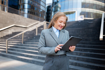 Business Professional Engages With a Tablet Amid Modern Architecture in an Urban Setting, Showcasing the Blend of Technology and Corporate Lifestyle