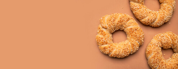Simit or gevrek, round bagel with sesame seeds on brown background top view. Creative layout with...