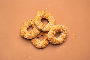 Simit or gevrek, round bagel with sesame seeds on brown background top view. Creative layout with...