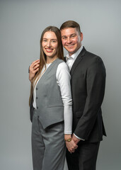 Trendy young couple smiling at each other in studio. Man and woman dressed stylishly, sharing warm, romantic connection. Concept of love, trust, and emotional closeness.