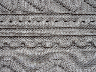 Neutral gray wool and cashmere knitwear with braid cable stitch knitted pattern, cozy winter textile background.