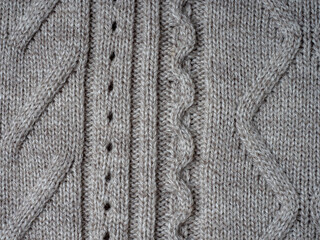 Neutral gray wool and cashmere knitwear with braid cable stitch knitted pattern, cozy winter textile background.