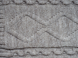 Neutral gray wool and cashmere knitwear with braid cable stitch knitted pattern, cozy winter textile background.