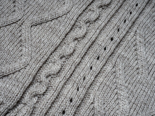 Neutral gray wool and cashmere knitwear with braid cable stitch knitted pattern, cozy winter textile background.