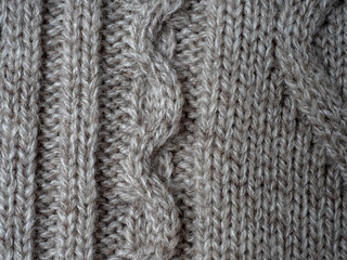 Neutral gray wool and cashmere knitwear with braid cable stitch knitted pattern, cozy winter textile background.
