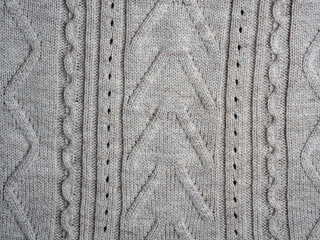 Neutral gray wool and cashmere knitwear with braid cable stitch knitted pattern, cozy winter textile background.