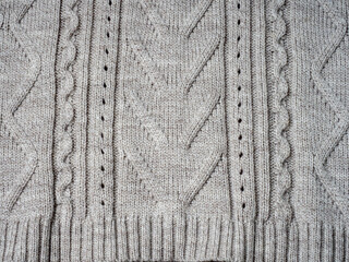 Neutral gray wool and cashmere knitwear with braid cable stitch knitted pattern, cozy winter textile background.