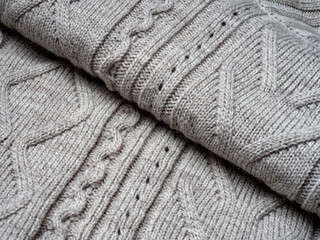 Neutral gray wool and cashmere knitwear with braid cable stitch knitted pattern, cozy winter textile background.
