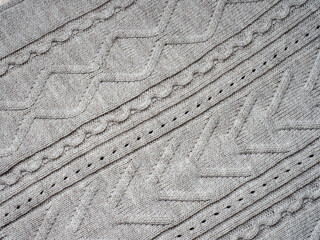 Neutral gray wool and cashmere knitwear with braid cable stitch knitted pattern, cozy winter textile background.