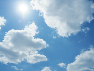 Bright hot sun on a blue summer sky with cloud shapes, weather or hot summer concept