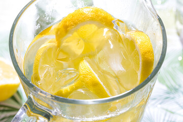 Refreshing pitcher of cold lemonade with ice cubes and lemon slices