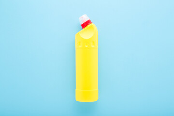 New yellow toilet cleaner bottle on light blue table background. Pastel color. Disinfection detergent. Closeup. Top down view.