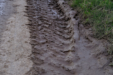 Muddy road with deep vehicle tracks after heavy rain and melting snow, Deep tire tracks in wet, muddy slush, Muddy terrain with tire impressions, challenges of off-road environments