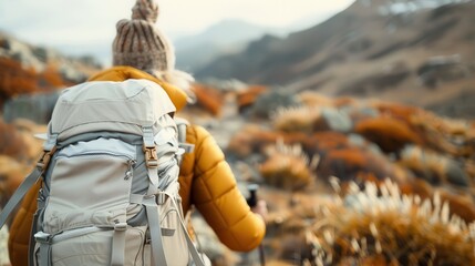 A solo traveler braving the rugged terrain adorned by vibrant fall colors while carrying a backpack and trekking pole showcases the spirit of adventure and exploration.