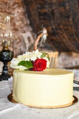 Elegant white cake with red rose decoration in rustic setting
