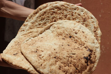Hands holding moroccan amazigh bread known as Tafarnout bread or tafournout bread