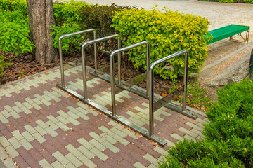 Outdoor bike parking. Bike rack in the park near the bushes - iron structure made of chromed pipes