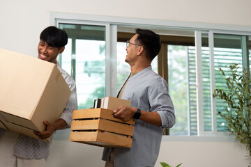 Gay couple moving in together, sharing joyful moments while unpacking boxes