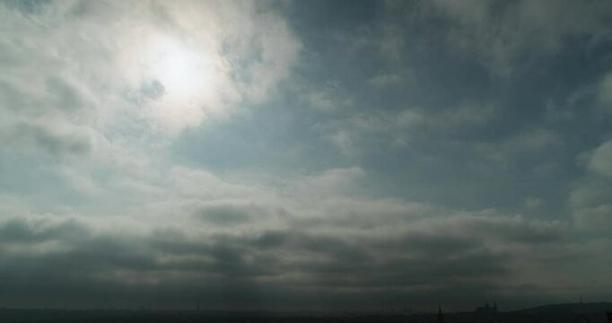 Dreamy Sky Over a Low Dark Horizon with a Distant Prague Castle Silhouette as Airy White Clouds Drift Sometimes Veiling the Sun on a Pale Blue Canopy in a Serene 4K Time Lapse