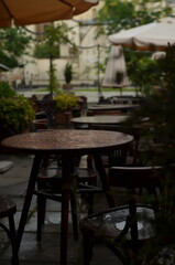 A beautiful street restaurant with vintage wooden tables and umbrellas during the rain.