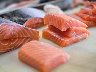 Fresh salmon fillets neatly sliced and stacked on a clean surface, showcasing the rich orange color and marbling texture, ideal for sushi, sashimi, or cooking preparations.