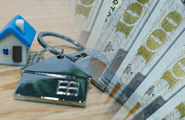 House keychain on a background of money. The concept of price changes on the real estate market. 