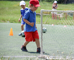 little three-year-old boys plays football at a sports school .