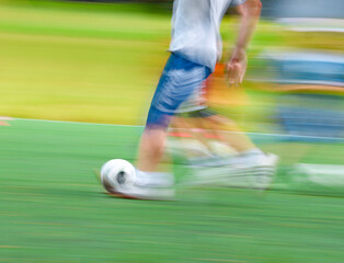 football player runs on a green field with a ball. Blurred.