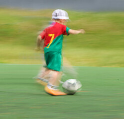 little three-year-old boy plays football at a sports school .