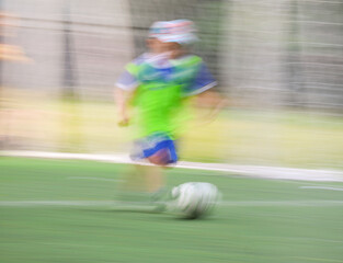 little four -year-old boys plays football at a sports school .Blur.