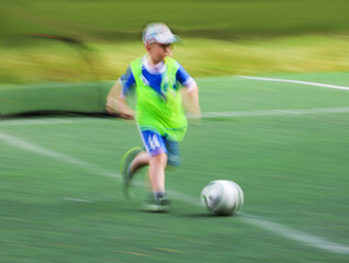 little four -year-old boys plays football at a sports school .Blur.