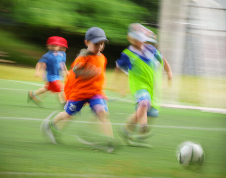 little four -year-old boys plays football at a sports school .Blur.