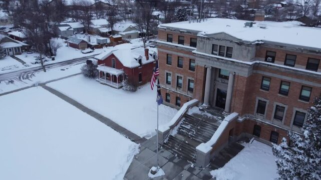Fly to American flag in front of courthouse in winter 
