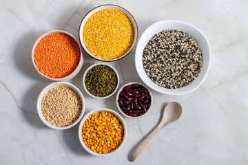 various Indian lentils and beans including masoor dal, moong dal, urad dal (with and without skin), moong whole, chana dal, and rajma, beautifully arranged in bowls on a marble surface 