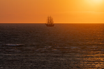 A majestic sailboat in the Baltic Sea against a golden sunset. Silhouette of a historic ship...