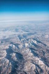 Aerial view of a snowy mountain range under a blue sky
