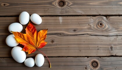 white and orange stones with autumn leaf arranged on wooden surface, positioned on the left with clear copy space on the right.