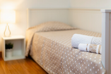 Room with a 90cm grey wooden trundle bed, white square nightstand, lamp and white wall, bath towels, rental house, vacation rental, bedroom