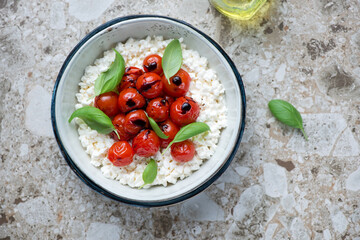 Bowl of caprese with cottage cheese on a light-brown granite background, horizontal shot, above view