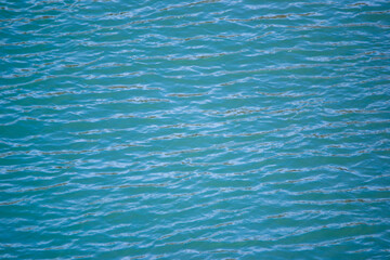 A calming, high-angle view of water with gentle ripples creating a beautiful, natural blue and turquoise patterned texture across the entire surface.